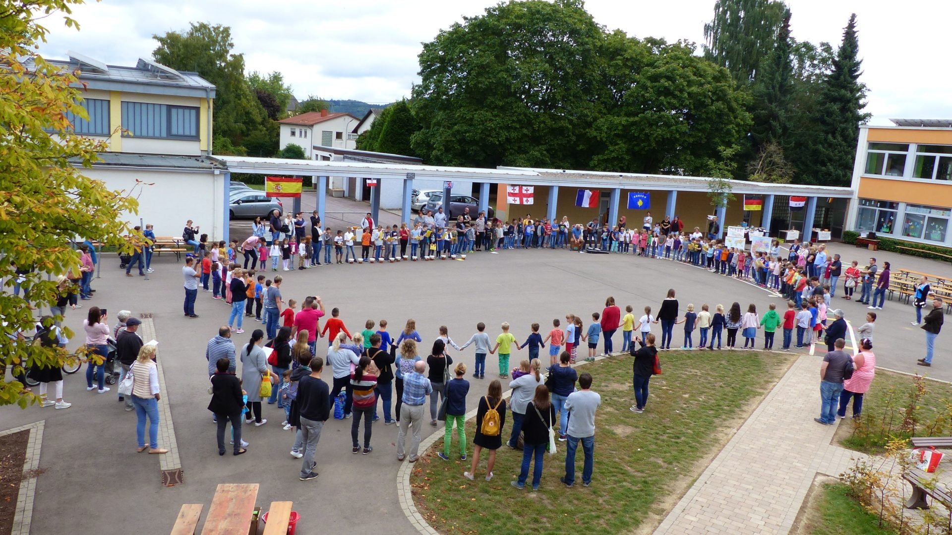 Das Foto zeigt die Schülerinnen und Schülern mit Eltern und Lehrpersonal auf dem Schulhof der Grundschule Saargau.