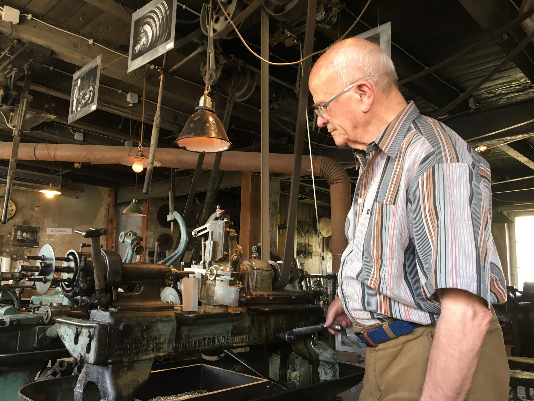 Das Foto zeigt einen Mann, der eine alte Maschine im Feinmechanischem Museum Fellenbergmühle betätigt.