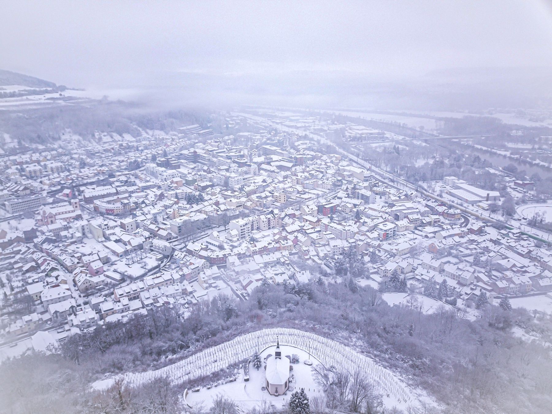 Das Foto zeigt eine Luftaufnahme der verschneiten Kernstadt von der Kreuzbergkapelle.