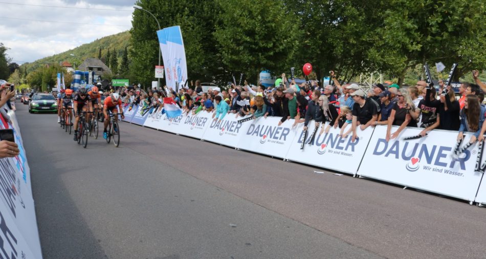 Das Foto zeigt Teilnehmer der Deutschland Tour mit jubelnden Zuschauern am Straßenrand.