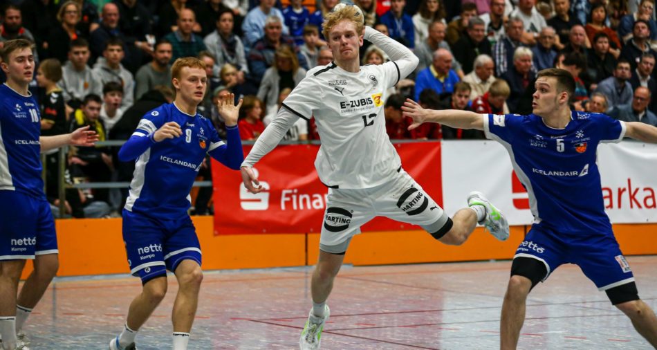 Das Foto zeigt eine Spielszene aus dem Finalspiel Deutschland gegen Island. Ein deutscher Spieler springt mit dem Ball in der Hand hoch, ein isländischer Spieler versucht, ihn abzuwehren.