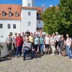 Das Foto zeigt einige Teilnehmende der Partnerschaftstage in Luckau 2023, im Hintergrund ist das Wasserschloss in Luckau zu sehen.