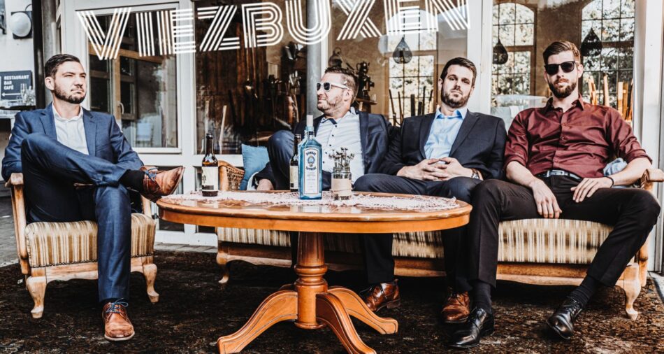 Das Foto zeigt die vier Jungs von Viezbuxen, drei sitzen lässig auf einem Sofa, einer lässig auf einem Sessel.