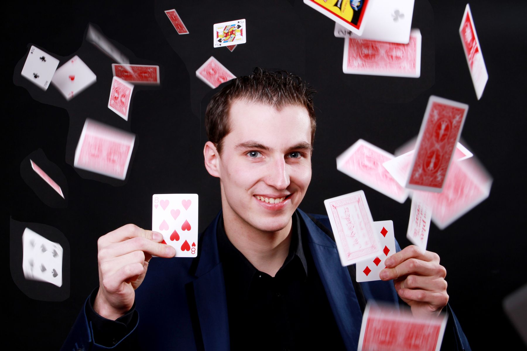 Zauberer Maxim Maurice, um ihn herum fliegen Spielkarten