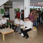 Erwachsene und Jugendliche im Rathaus-Foyer, um sie herum stehen Stelen mit Plakaten