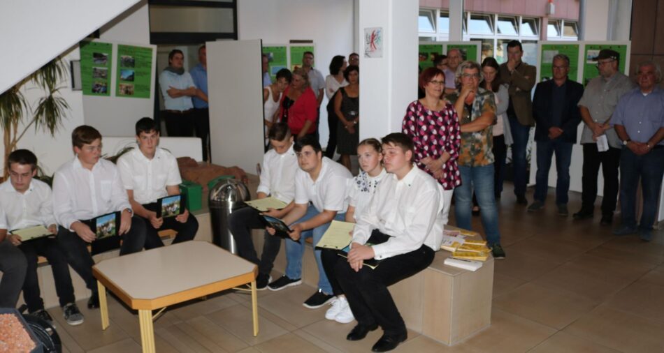 Erwachsene und Jugendliche im Rathaus-Foyer, um sie herum stehen Stelen mit Plakaten