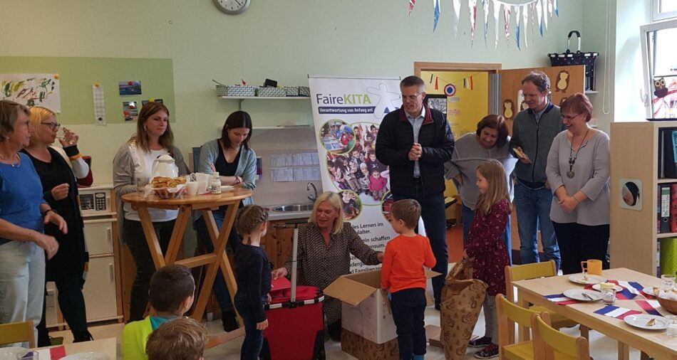 Kinder und Erwachsene in einem Kindergartenraum, Kinder packen Geschenke aus