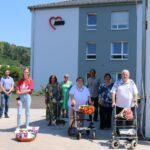 Jugendliche, Erwachsene und Senioren mit fairen Rosen vor einem Seniorenheim