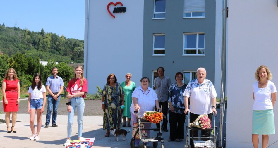 Jugendliche, Erwachsene und Senioren mit fairen Rosen vor einem Seniorenheim