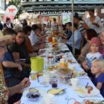 Lange, voll besetzte Tafel in der Fußgängerzone, Menschen speisen