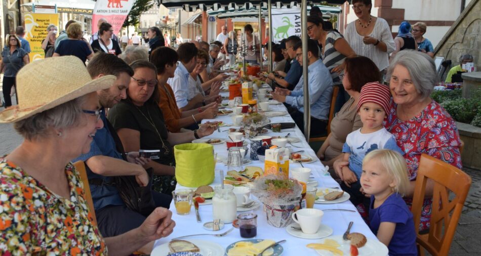 Lange, voll besetzte Tafel in der Fußgängerzone, Menschen speisen