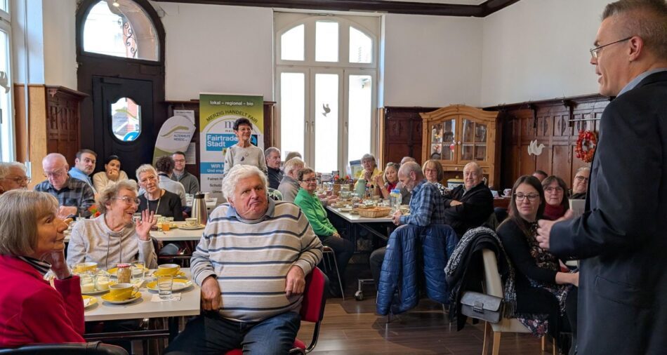 Menschen sitzen an Frühstückstischen, sie hören Oberbürgermeister Marcus Hoffeld zu