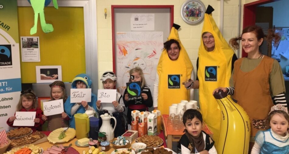 Verkleidete Kinder und Erzieherinnen vor einem Frühstücksbuffet