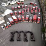 Luftbild (zahlreiche Feuerwehrkameraden bilden das Logo der Kreisstadt Merzig; im Hintergrund steht der Fuhrpark der Feuerwehr)