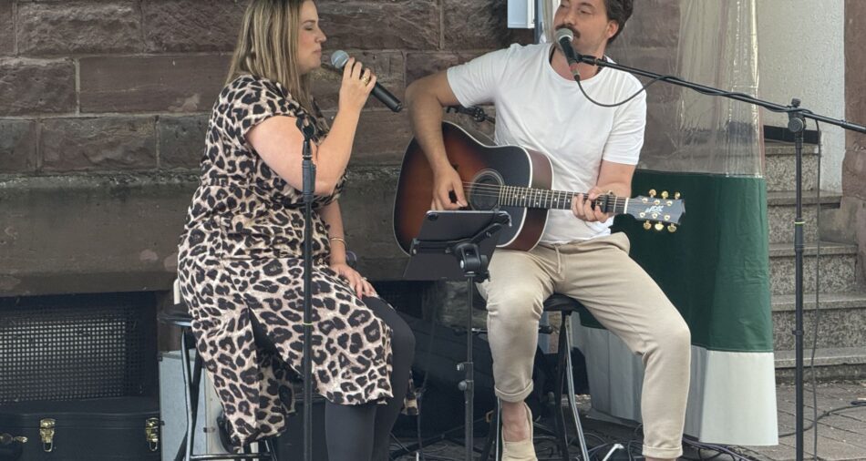 Eine Musikerin mit Mikrofon und ein Musiker mit Gitarre beim Kleinkunstsommer 2025
