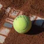 Ein Tennisball liegt auf einem staubigen Platz