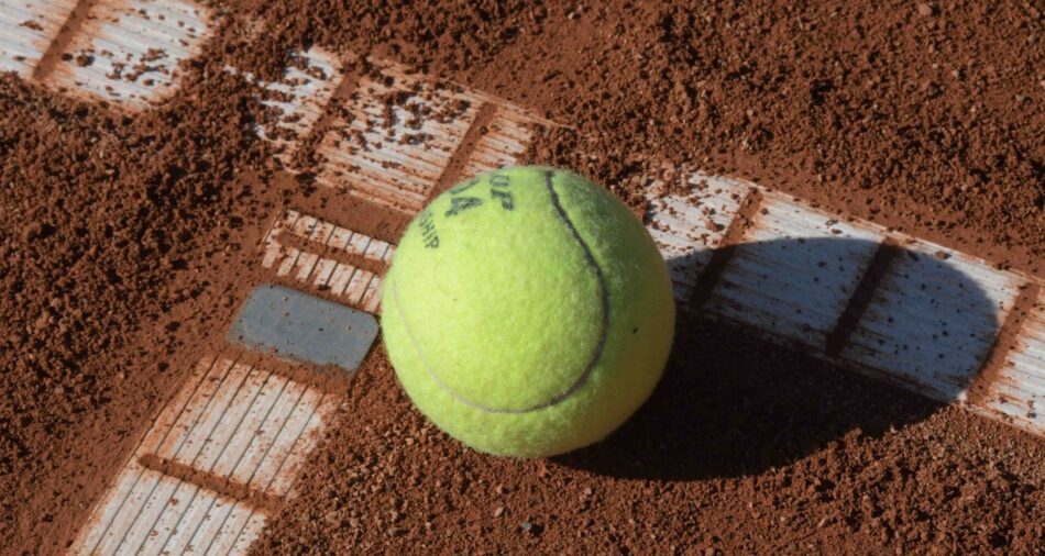Ein Tennisball liegt auf einem staubigen Platz
