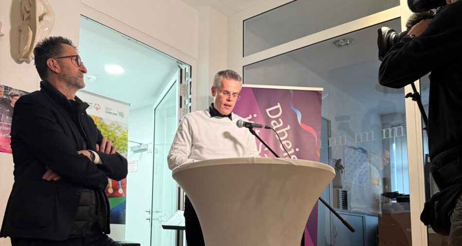 Oberbürgermeister Marcus Hoffeld spricht ins Mikrofon, eine Fernsehkamera ist auf ihn gerichtet, neben ihm steht Minister Jost