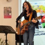 Sonja Hewer singt mit geschlossenen Augen ins Mikrofon, sie spielt Gitarre