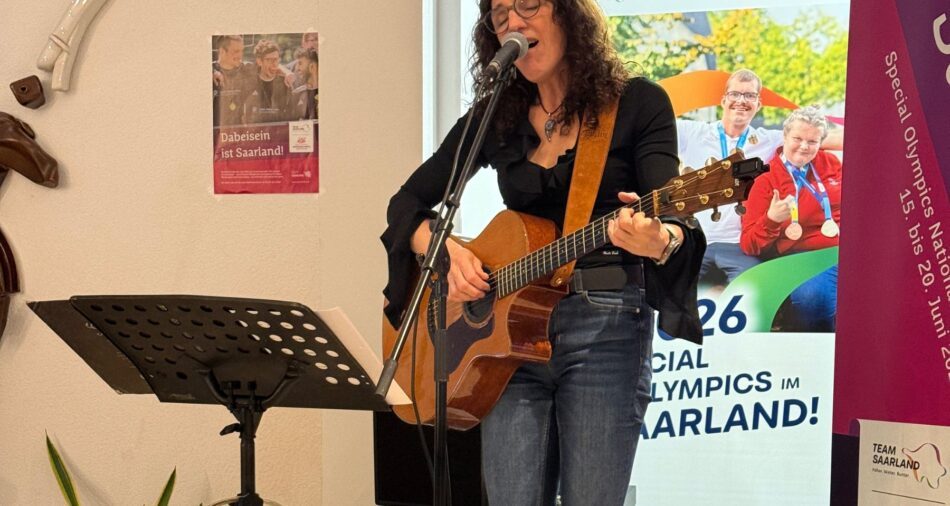 Sonja Hewer singt mit geschlossenen Augen ins Mikrofon, sie spielt Gitarre