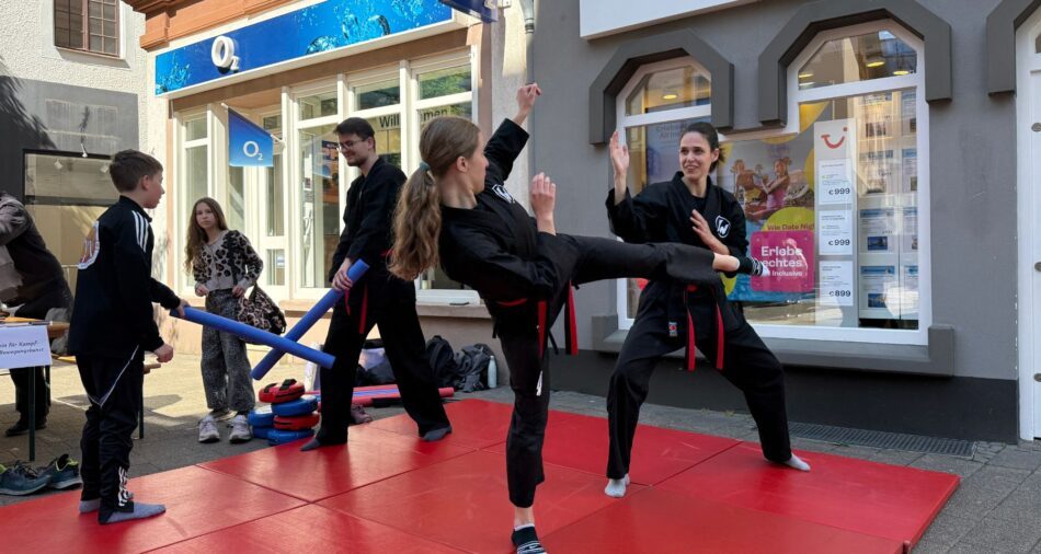 Zwei Mädchen und zwei Jungen führen Kampfsporttechnik vor