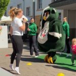 Mädchen und Maskottchen der KG Humor tanzen gemeinsam