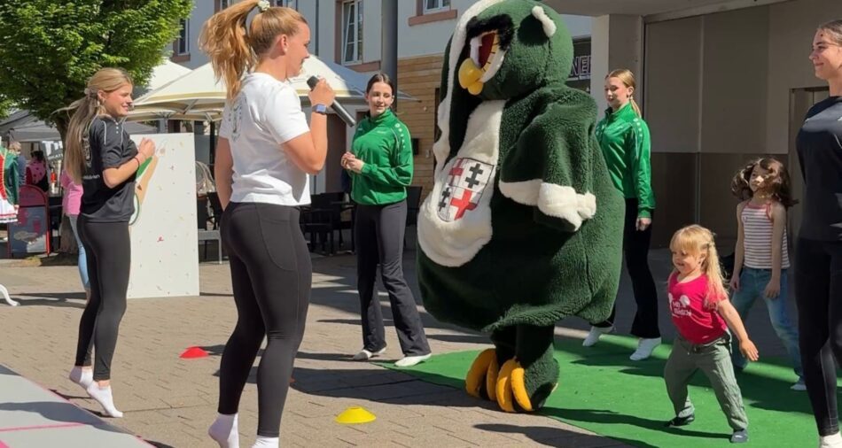 Mädchen und Maskottchen der KG Humor tanzen gemeinsam