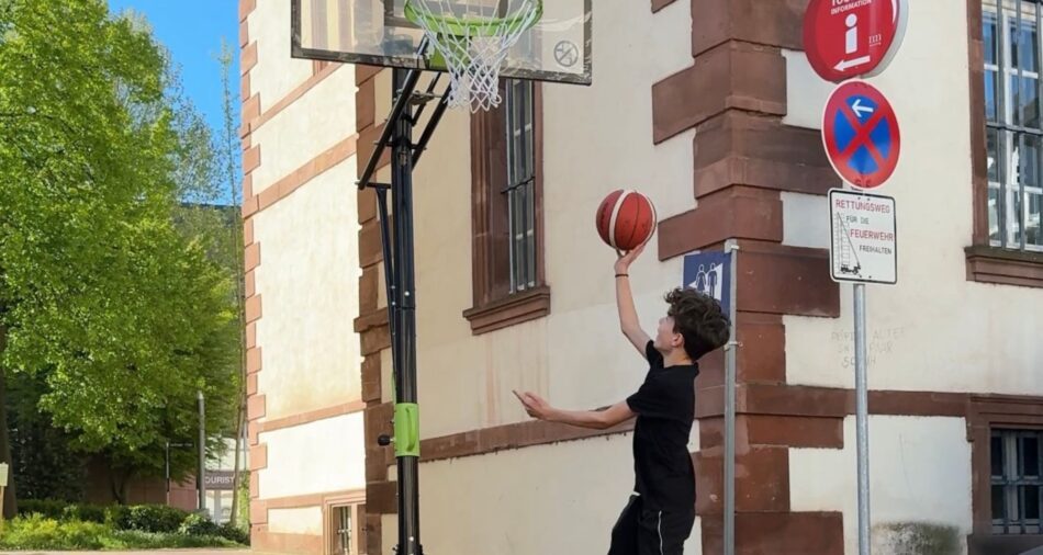 Junge wirft einen Basketball in einen Basketballkorb