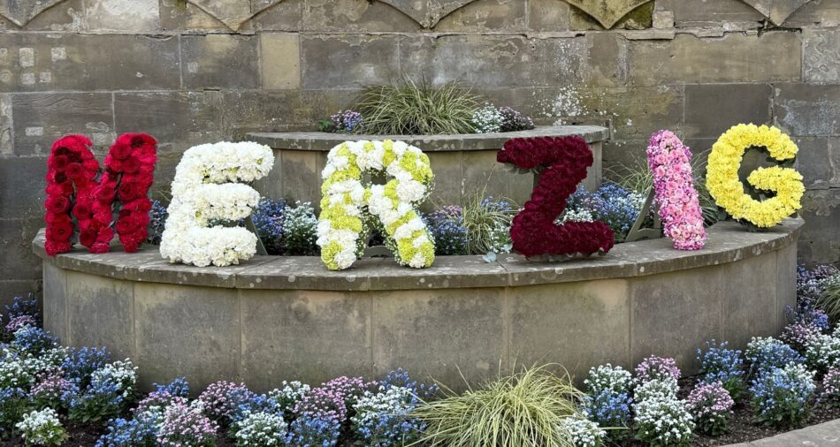 Buchstaben aus bunten Blumen ergeben das Wort Merzig