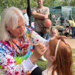 Kind wird von einer Frau geschminkt