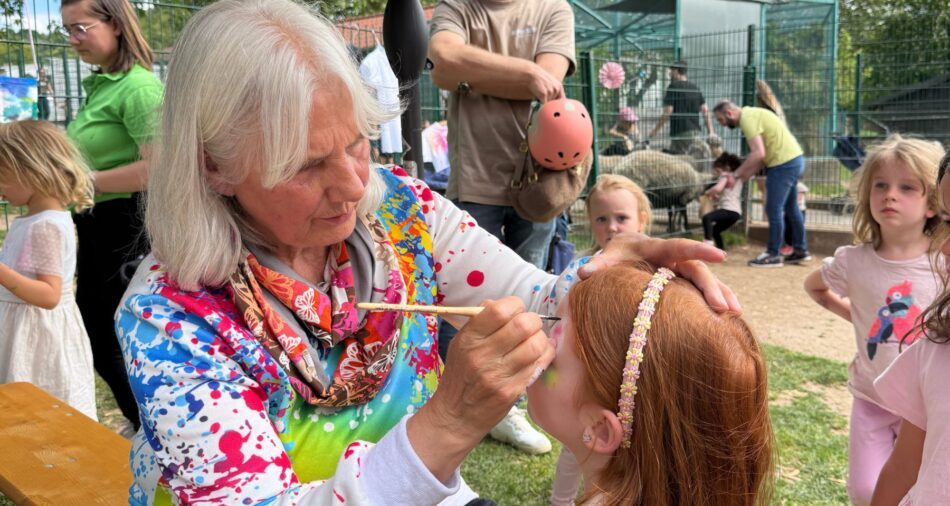 Kind wird von einer Frau geschminkt