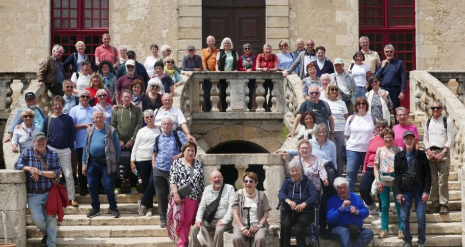 Zahlreiche Menschen posieren vor einem historischen Gebäude