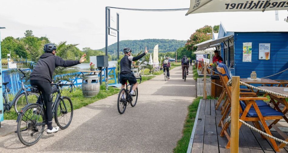 Männer auf Fahrrädern winken fröhlich zur Seite