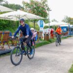 Mann auf Fahrrad, kleines Mädchen im Kindersitz, winkt fröhlich in die Kamera