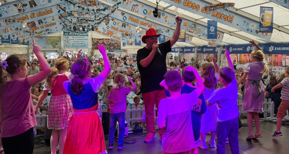 Markus Becker tanzt auf der Bühne mit Kindern beim Oktoberfest